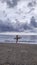 Foreign tourist ready to surf at changgu beach before sunset in cloudy weather on the island of bali