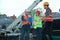 Foreman with clipboard and engineers in safety equipment at construction site