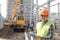 Foreman construction worker standing  smiling with new building site in the background