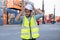 Foreman engineer or cargo container worker hold hardhat and stand in front of cranes and stack of shipping. Logistic shipyard