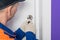 Foreman fixing the lock of the white front door, close-up