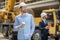 Foreman holding coffee cup, building supervisor standing behind him with tablet