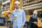 Foreman holding coffee cup, smiling, building supervisor standing behind him with tablet