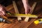 The foreman measures the distance with a construction tape on a wooden board with a construction tape. Builder hands close up.