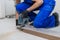 A foreman in overalls cuts planks and lays laminate flooring