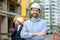 Foreman standing with folded arms, building supervisor standing behind him, looking at the building