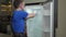 Foreman in uniform tries to fix broken fridge in kitchen