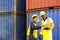 Foreman using laptop computer in the port of loading goods. Foreman talking with worker or laborer in the Industrial Container