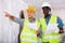 Foreman and worker in yellow vest and protective helmet are discussing the repair of a room in cottage