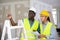 Foreman and worker in yellow vest and protective helmet are discussing the repair of a room in cottage