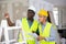 Foreman and worker in yellow vest and protective helmet are discussing the repair of a room in cottage