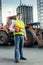 Foreman in yellow jacket posing next to bulldozer on building s