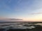 Foreshore at sunset with rocks and seaweed. Pink reflections