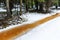 Forest ditch with yellow-brown water in snowy winter thaw day