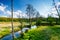 Forest edge near small river in countryside. Blue sky