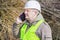 Forest engineer talking on cell phone near pile of twigs