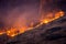 Forest fire and smoke on mountains at night.