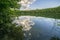 Forest lake in the evening, reflected in the water surface of the sky with clouds and trees