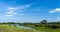 Forest landscape on the background of an unusual small river in the middle of the field