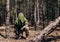 Forest sniper in camouflage sitting with rifle