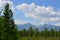 Forest, snowy mountains and clouds on blue sky - siberian alps