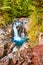 Forest surrounds peaceful blue waterfalls into rocky canyon