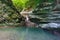 Forested slope overgrown with ivy and moss with waterfall flowing down