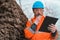 Forestry technician reading notes on clipboard notepad paper in forest