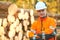 Forestry worker in protective workwear in front of wood lumber cut tree