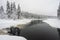 Foresty winter lake or pond in the woods. Trees reflections. Snow covered woods background. Tall trees pines, firs in woods stand