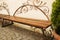 Forged brown wooden bench in the park with cobbles