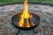 Forged fire basket with warming fire on beautiful paving stone circle in the garden