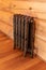 Forged Radiator in retro style in wooden logs room, room interior, wooden floor and wall, Central heating installation, warm home