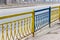 Forged steel metal fencing at roadway in center of Dnipro city painted in colors of national flag of Ukraine is yellow and blue.