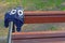 Forgotten child cap with cute monster face with big eyes hangs on wooden bench