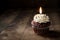 A forgotten cupcake with a lit candle the flame dancing merrily