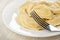 Fork, boiled dumplings in white plate on wooden table