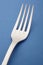 Fork detail over a blue textured background. Cutlery