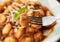 Fork with italian pasta gnocchi with bolognese sauce over unfocused background