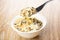 Fork of julienne with chicken, mushroom above bowl on table