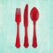 Fork, knife and spoon cutlery in red on turquoise wood background