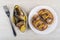 Fork, pieces of smoked mackerel with lemon in bowl, sandwiches with fish in plate on table. Top view