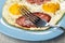 Fork on plate with fried eggs with sausage on wooden table