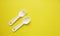Fork and spoon on a yellow background. Plastic utensils. Tableware for games. Meals, lunch. Children is set of dishes