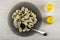 Fork in transparent plate with boiled dumplings, greens, salt and pepper on wooden table. Top view