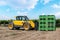 Forklift loader loads plastic boxes in a field on a vineyard background outdoor.