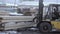 Forklift loader picks up stack of wood planks at sawmill factory yard