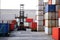 Forklift truck handling cargo container boxes in logistic delivery yard with stacks of cargo containers in background