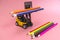 A forklift truck holds colored pencils on a platform and loads them onto a stack from below. The concept of logistics and delivery