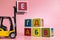 A forklift truck holds a cube with a letter of the Russian alphabet on the platform and collects words from them on a pink